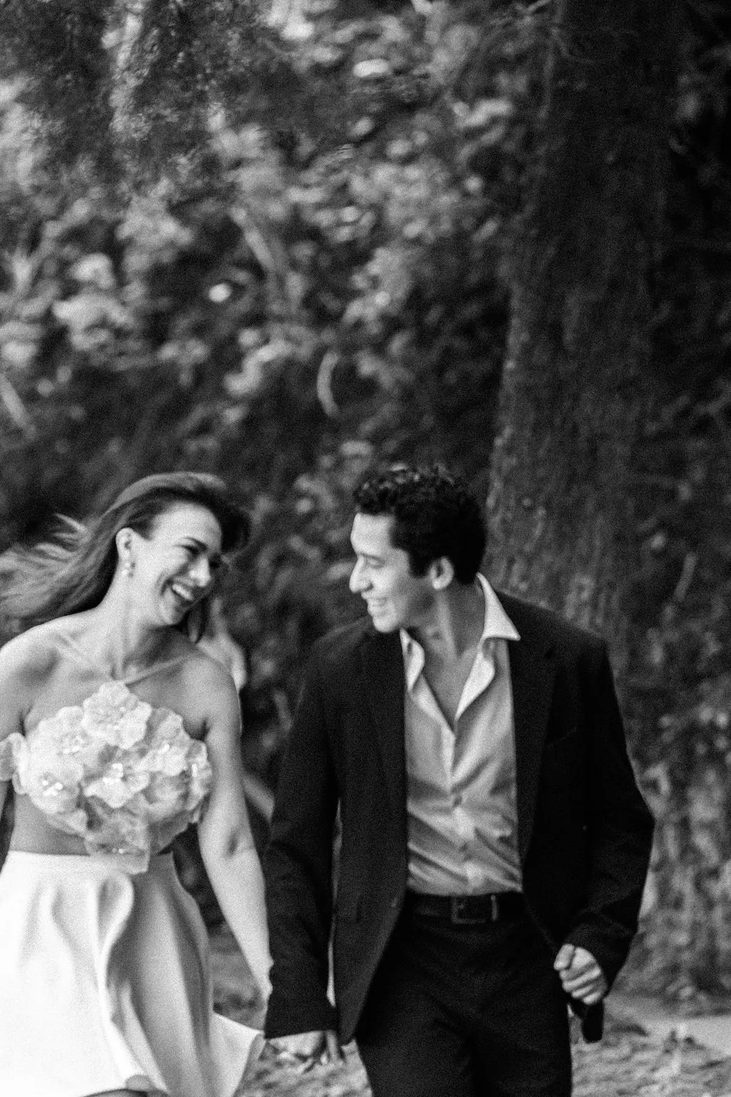 En blanco y negro, Fátima y Emerson ríen mientras caminan de la mano